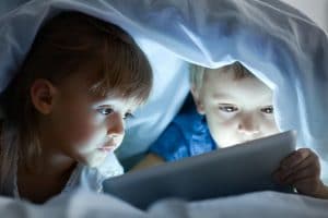 kids under blanket looking at tablet